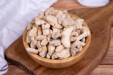 Dried Organic Ginger root on wooden background. Sun-dried ginger root or Dry Adrak in wooden bowl