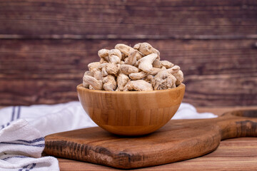 Dried Organic Ginger root on wooden background. Sun-dried ginger root or Dry Adrak in wooden bowl