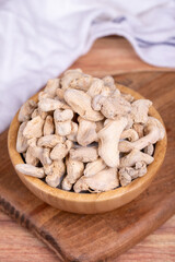 Dried Organic Ginger root on wooden background. Sun-dried ginger root or Dry Adrak in wooden bowl
