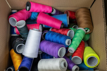 Top view shot. A spool of thread is used for the production of clothes in boxes of various colors such as purple, white, yellow, blue, black, brown, orange, green and red in the sewing industry.