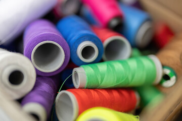 Spools of thread stacked together in different colors, yellow, blue, green, purple, white and red, in a cardboard box. beautiful eye-catching colors Used for weaving in the sewing industry