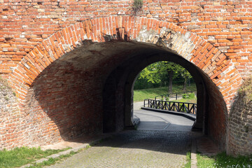 Archway in the fortress wall. Bridge and a landscape behind the wall.