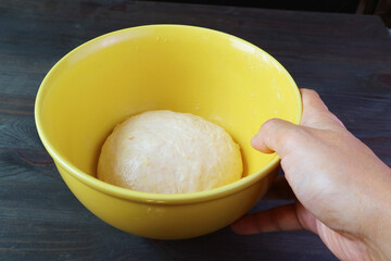 Man's hand placing a bowl of kneaded dough on the table to let it rises before baking