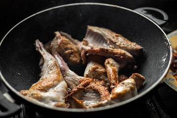 Raw rabbit with spices in a pan. Cooking stewed rabbit.