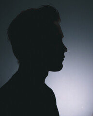 A silhouette of a man deep in thought in a dark room