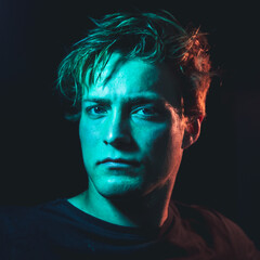 Creative orange and teal light portrait shots of a man in a dark room