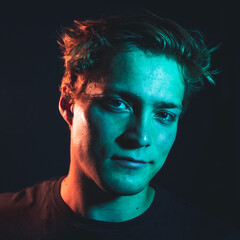 Creative orange and teal light portrait shots of a man in a dark room