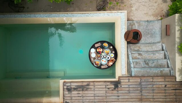 Aerial view of Luxurious floating breakfast in private pool. Special menu with floating pool tray for exotic summer holidays. Floating breakfast tray contains food and beverage is drifting in pool