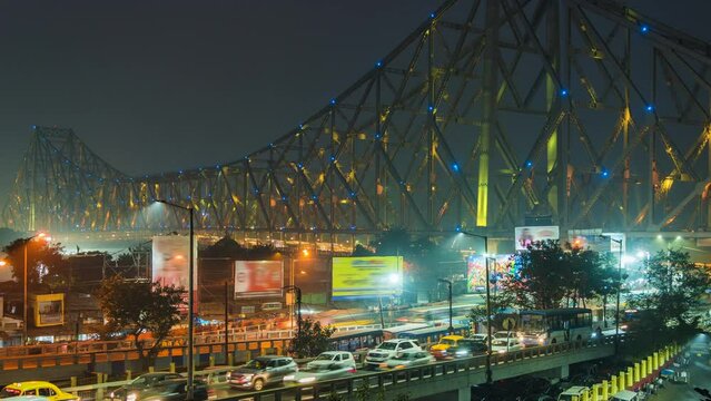 Timelapse view of traffic exiting architectural landmark Howrah Bridge illuminated at night in Kolkata, West Bengal, India, zoom in. 