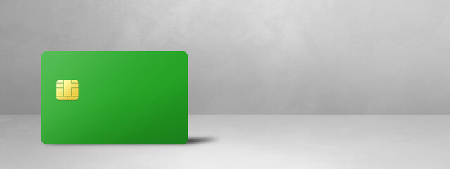 Green credit card on a white concrete background