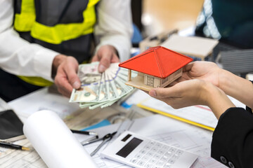 Fototapeta premium Close up hands holding banknotes and house model , real estate and loaning concept