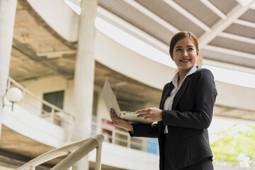 Confident young Asian businesswoman using tablet in office building,  modern working woman concept