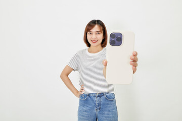 Young Asian female in t-shirt and blue jeans showing smartphone
