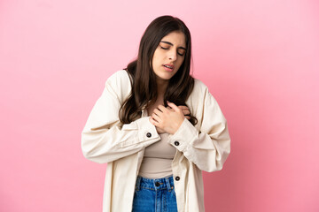 Young caucasian woman isolated on pink background having a pain in the heart