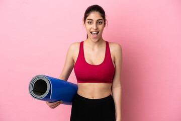 Young sport caucasian woman going to yoga classes while holding a mat with surprise facial expression