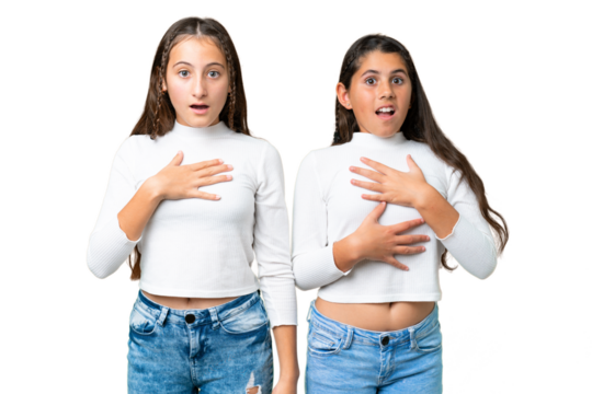 Friends girls holding gift and a birthday cake over isolated chroma key background surprised and shocked while looking right
