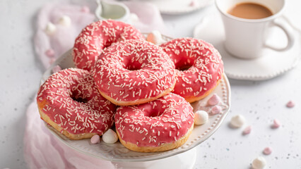 Homemade and delicious pink donuts and coffee topped with sprinkles.