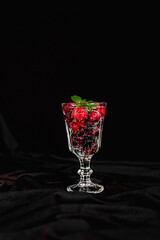 summer cocktail with cherry berries and mint sprigs in a transparent glass on a black background. space for text. soft drink