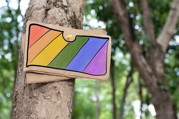 Cardboard which has rainbow drawing on the top was sticked and decorated on tree trunk in the public park to inform and to show respecting of humans gender diversity in pride month.