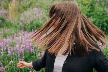 Beautiful natural hair. Woman shaking head, dancing on nature background.