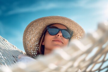 A woman wearing sunglasses sits on a beach chair with a blue sky behind her. Generative AI