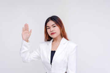 A serious young woman with one hand raised as an act of taking oath. Isolated on a white background.
