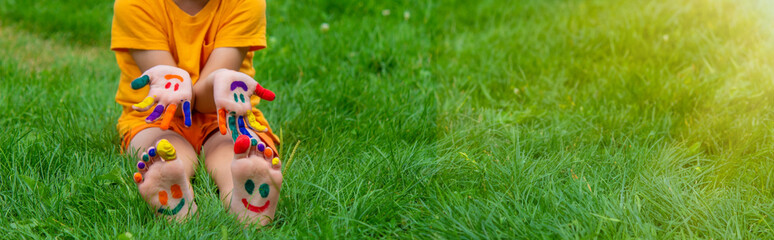 Children's hands in the colors of summer, a smile on the boy's palm.