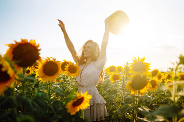 Beautiful woman posing in a field of sunflowers in a dress and hat.  Fashion, lifestyle, travel and...