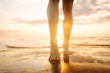 Woman leg close up walking on sand relaxing in beach at sunset. Sexy lean and tanned legs. Summer holidays.
