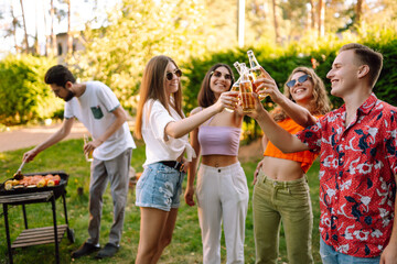 Group of young people  have fun and drink beer  in garden for picnic. Vacation, picnic, friendship or holliday concept.
