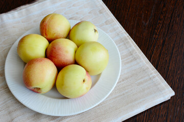 yellow nectarines on white plate on the kitchen table, copy space