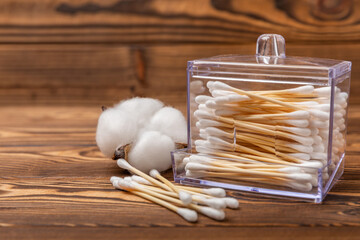 White cotton swabs on a brown wood background. Cotton buds. Bamboo cotton buds. Eco-friendly. Hygienic cotton swabs for ears. Place for text. Place to copy.