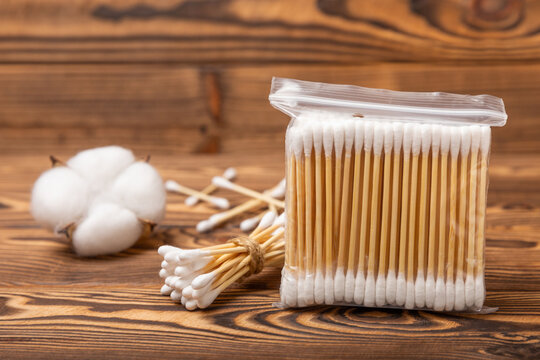White cotton swabs on a brown wood background. Cotton buds. Bamboo cotton buds. Eco-friendly. Hygienic cotton swabs for ears. Place for text. Place to copy.