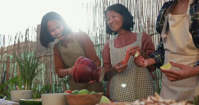 Asian family cooking thai dinner together while preparing papaya salad with fresh spicy dressing at home patio outdoor 