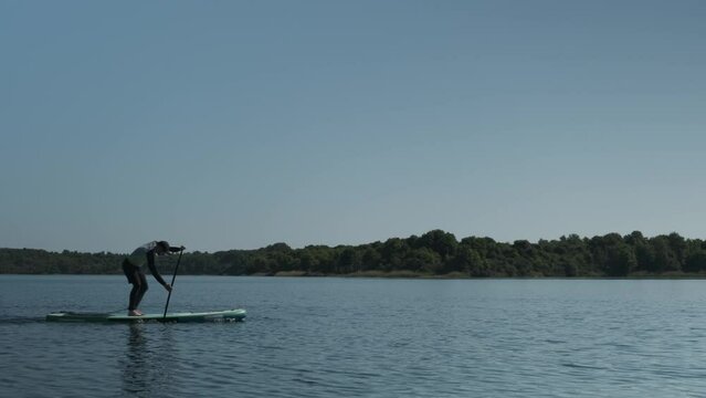 Man paddling on stand up paddle board on lake. SUP boarding 