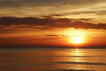 sun sets behind the horizon, a beautiful sea sunset. view low over the water. Bright red, orange sky over the ocean