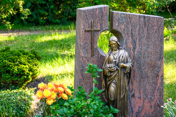 Geschmücktes Grab, Grabstein mit Kreuz und Figur 