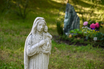 Statue Jungfrau Maria mit Kind vor Grab am Friedhof