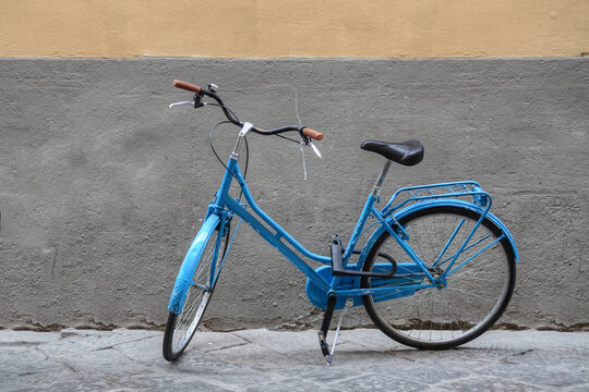 A light blue bicycle in front of a plaster wall 