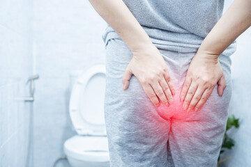 woman suffering from hemorrhoids hurting and bleeding
during bowel movements in a toilet 