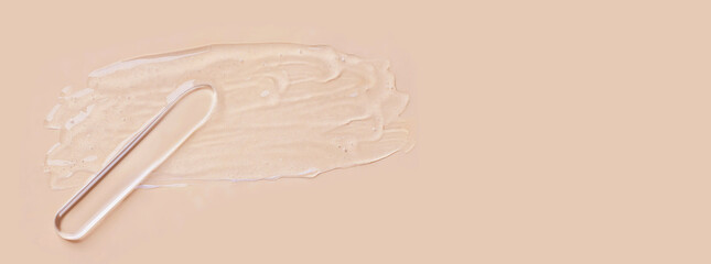 Transparent gel smeared on a beige background. Spatula for applying cream or gel.