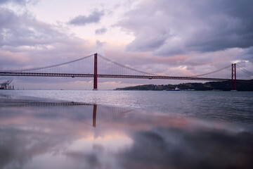 Beautiful evening landscape with suspension 25 April bridge over the Tagus river in Lisbon, Portugal.