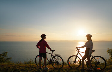 Two women with bicycles on the sea or lake shore