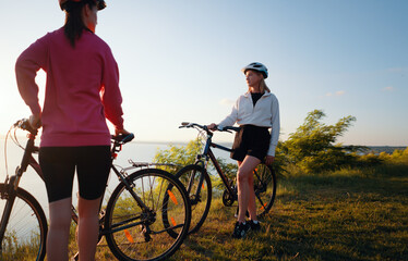 Obraz premium Two women with bicycles on the sea or lake shore