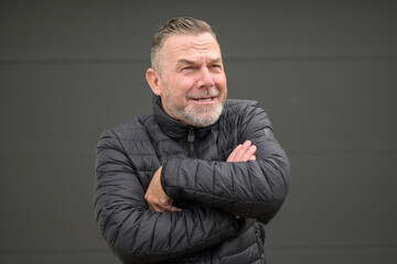 Middle age man with crossed arms looking to distance because of the weather