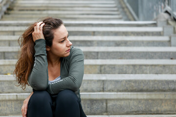 Disappointed and sad woman sitting on stairs. She sits alone and thinks on a sad and depressed on the stairs
