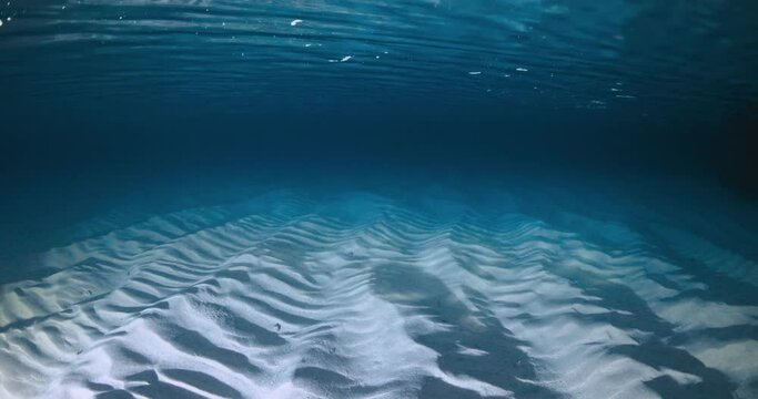 Transparent ocean with waves, sandy sea bottom underwater in night with a lantern