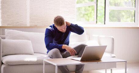 Man Working On Laptop Computer With Neck Injury Pain