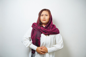 An Asian Muslim woman is fasting and hungry and touching her belly while looking aside thinking about what to eat