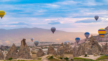 Fototapeta na wymiar Cappadocia. Hot air balloons flying over Cappadocia in a dramatic sky. Travel to Turkey. Selective focus included.